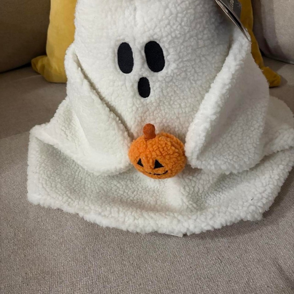 White ghost plush pillow with orange pumpkin face'